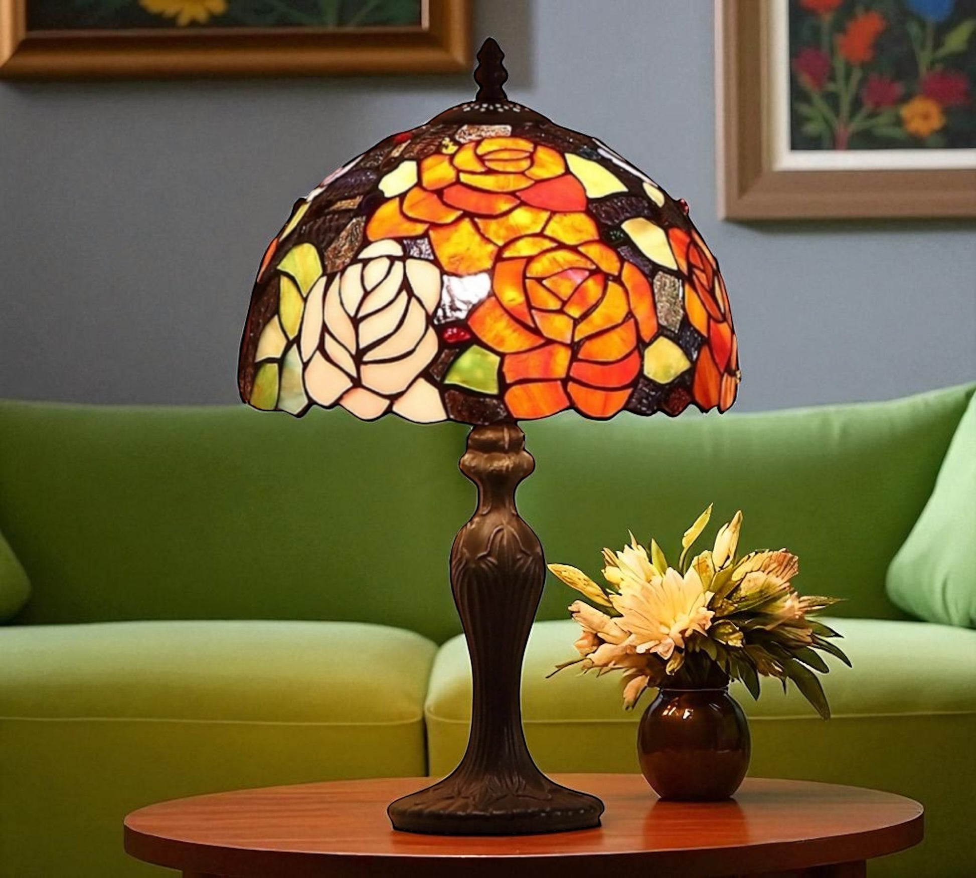 Stained glass lamp on a table with a green sofa and floral arrangement in the background. CDH Tiffany Table Lamp