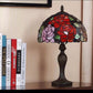 Decorative table lamp with stained glass shade featuring roses on a shelf with books. CDH Tiffany Table Lamp