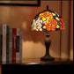 Stained glass lamp on a shelf with books in the background CDH Tiffany Table Lamp