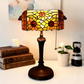 Tiffany table lamp with stained-glass floral shade and dark metal base, pull chain
