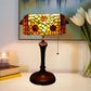 Stained-glass table lamp with yellow floral shade and dark metal pedestal base