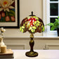 Tiffany-style stained glass table lamp with red flower shade and bronze base on a tabletop