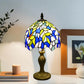 Tiffany table lamp with stained glass dome shade in blue, yellow, and white; bronze pedestal base