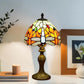 Tiffany-style stained glass table lamp with yellow-orange shade and dark metal base