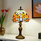 Tiffany-style table lamp with multicolor stained glass shade and decorative bronze-toned base
