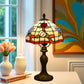 Tiffany-style stained glass table lamp with floral shade, bronze base, and pull-cord switch.