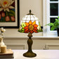 Tiffany-style stained glass table lamp with orange and green floral shade and dark metal base