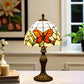 Tiffany table lamp with stained-glass shade showing orange butterfly wings, bronze base