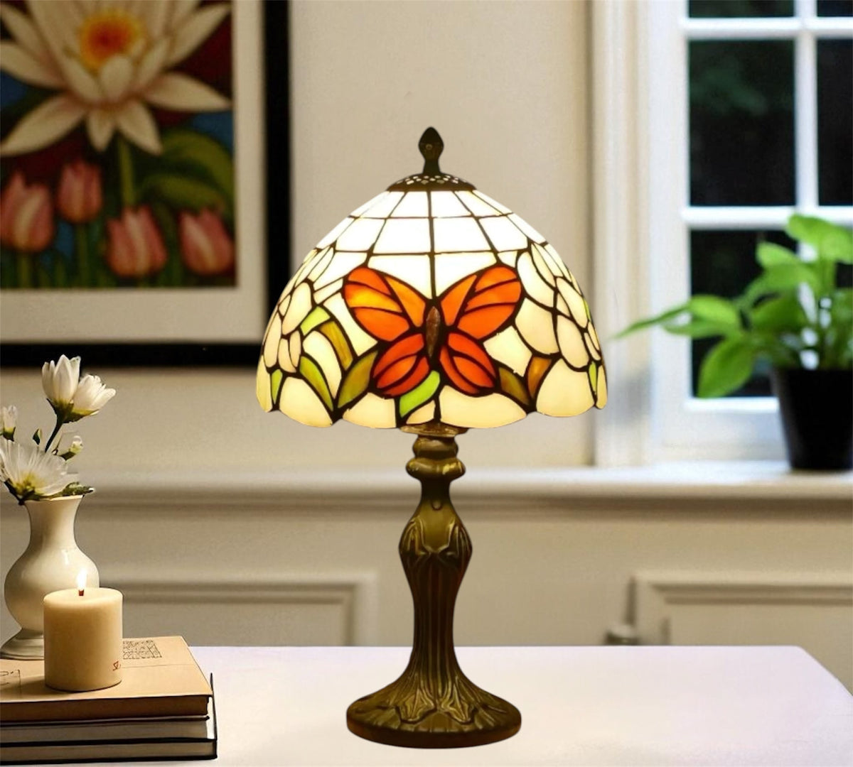 Tiffany table lamp with stained-glass shade showing orange butterfly wings, bronze base