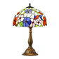 Stained glass table lamp with domed floral shade and bronze-toned pedestal base.