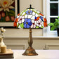Domed stained glass table lamp with colorful floral pattern and bronze-toned metal base.