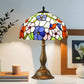 Colorful stained glass table lamp with domed floral shade and bronze-toned metal base.