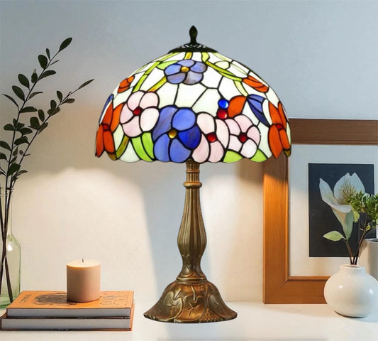 Colorful stained glass table lamp with domed floral shade and bronze-toned metal base.