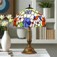Stained glass table lamp with domed floral shade and bronze-toned pedestal base.