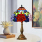 Stained glass table lamp with red rose shade, multicolor panels, bronze base, black finial.