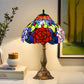 Stained glass Tiffany-style table lamp with floral rose shade and bronze metal base.