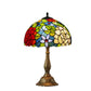 Tiffany-style stained glass table lamp, multicolor dome shade and bronze base on white background