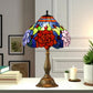 Multicolor stained glass table lamp with red floral center, bronze base, black top knob.