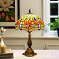 Tiffany table lamp with multicolor stained-glass shade and bronze base on a tabletop.