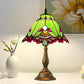 Table lamp with green stained-glass shade, red accents, and bronze base