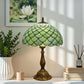 Tiffany-style table lamp three-quarter view with green stained-glass shade and bronze base