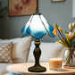 Stained glass table lamp with glowing blue shade and ornate bronze base