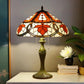 Tiffany table lamp with multicolor stained glass shade and bronze base on white surface