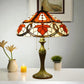 Tiffany table lamp with stained glass shade, bronze base with ornate foot, small candles nearby