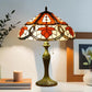 Tiffany table lamp with stained glass shade and bronze base, lit on tabletop