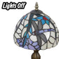 Close-up of unlit stained-glass dome shade with blue and gold accents on metal finial