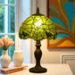 Green Tiffany table lamp with lit stained-glass dome shade and dark metal base