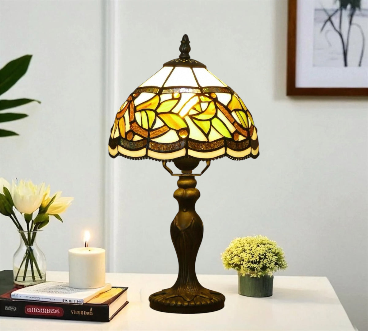 Tiffany-style table lamp with yellow stained glass shade and bronze metal base on table.