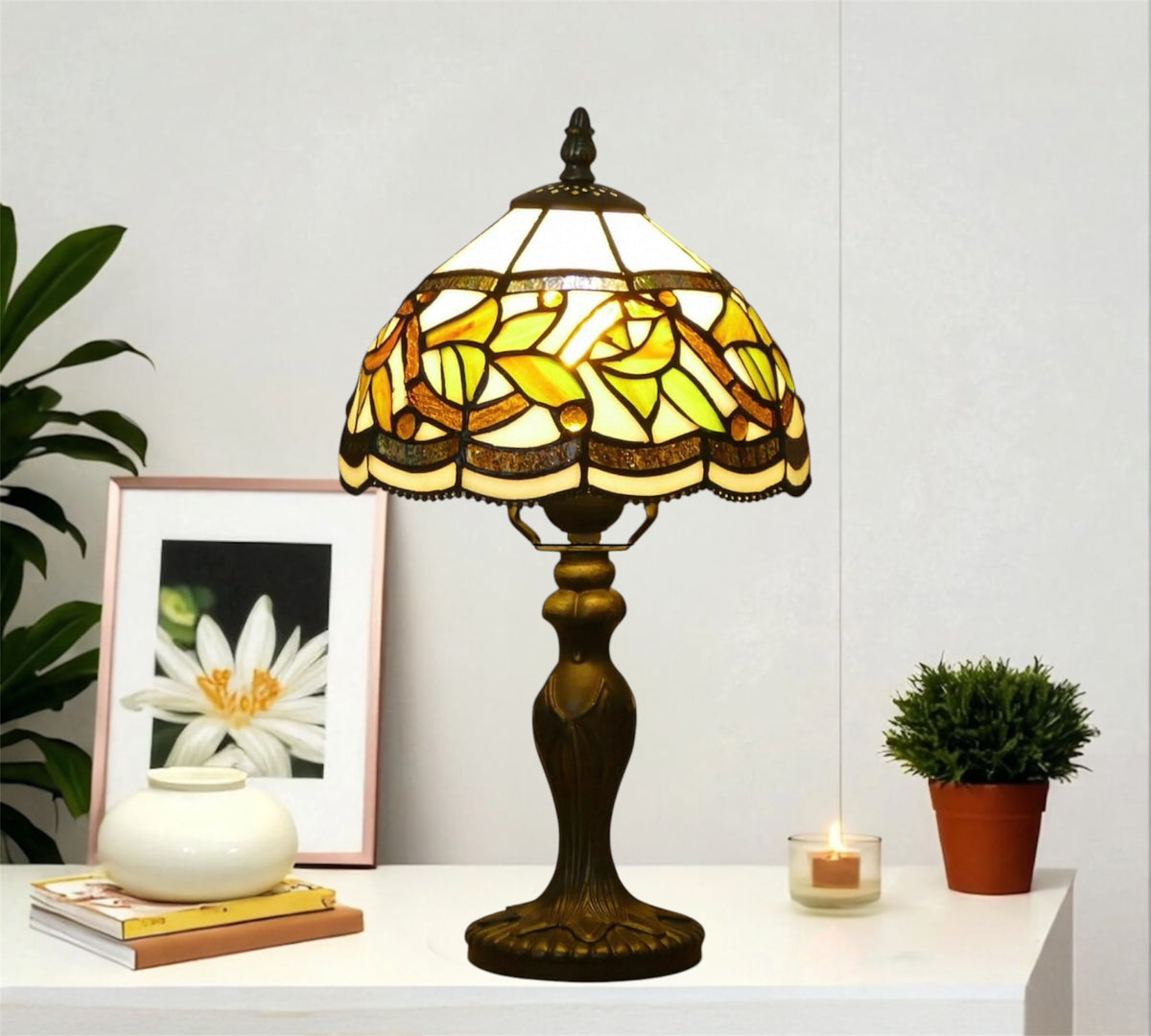 Tiffany-style stained glass table lamp with yellow shade and bronze metal base on sideboard.