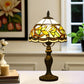 Tiffany-style table lamp with yellow stained glass shade and bronze base, lit from inside.