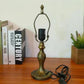 Tiffany-style table lamp base with decorative finial and bronze gold base on tabletop