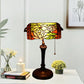 Stained glass table lamp with floral shade in amber, red, and yellow; dark metal base