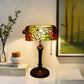 Stained glass table lamp with floral shade in warm amber and red panels; dark base