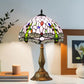 Stained-glass table lamp featuring a multicolor dome shade and bronze pedestal base