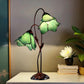 Green stained glass water lily table lamp with three lit flower shades and metal base